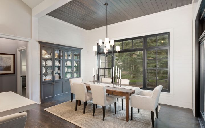 a dining area with a table, six chairs, nice lighting, glass windows, and carpeting in the middle.